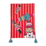 a striped christmas tea towel with four nutcracker motifs and blue and pink tasseled corners.