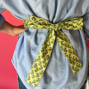 Person wearing a light blue shirt with a green patterned bow tie against a red background