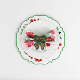 Lifestyle shot of the cottage grove geranium red floral plate with a white plate resting on it, holding a napkin with rattan ribbon napkin ring.