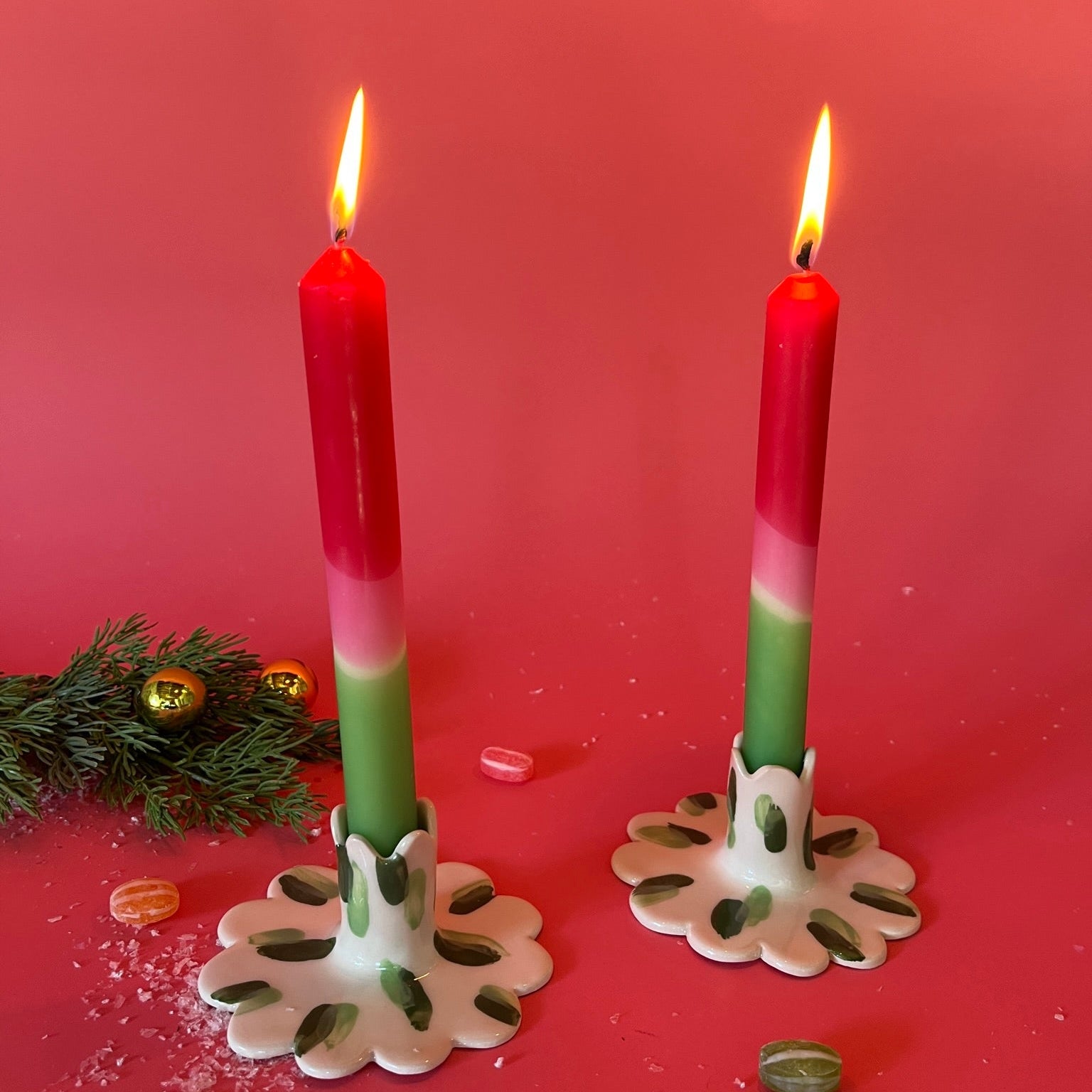 lighted 2 Red white green Taper Candles in a holder with red background