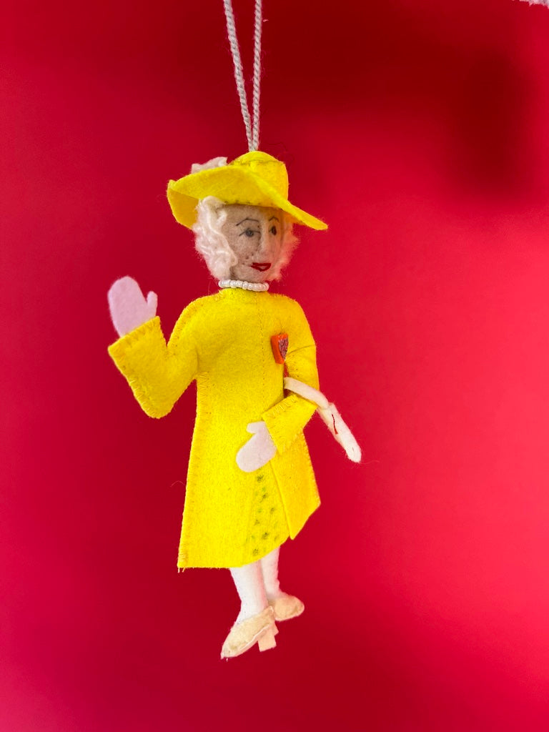 Decorative ornament of Queen Elizabeth in a yellow outfit on a red background