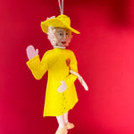 Decorative ornament of Queen Elizabeth in a yellow outfit on a red background