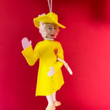 Decorative ornament of Queen Elizabeth in a yellow outfit on a red background