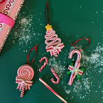 Set of three colorful candy-themed Christmas ornaments shaped like candy canes, lollipops, and Christmas trees