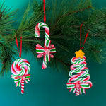 Set of three colorful candy-themed Christmas ornaments shaped like candy canes, lollipops, and Christmas trees