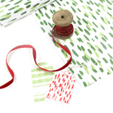 Styled display of green brushstroke wrapping paper with gift tags and red ribbon.