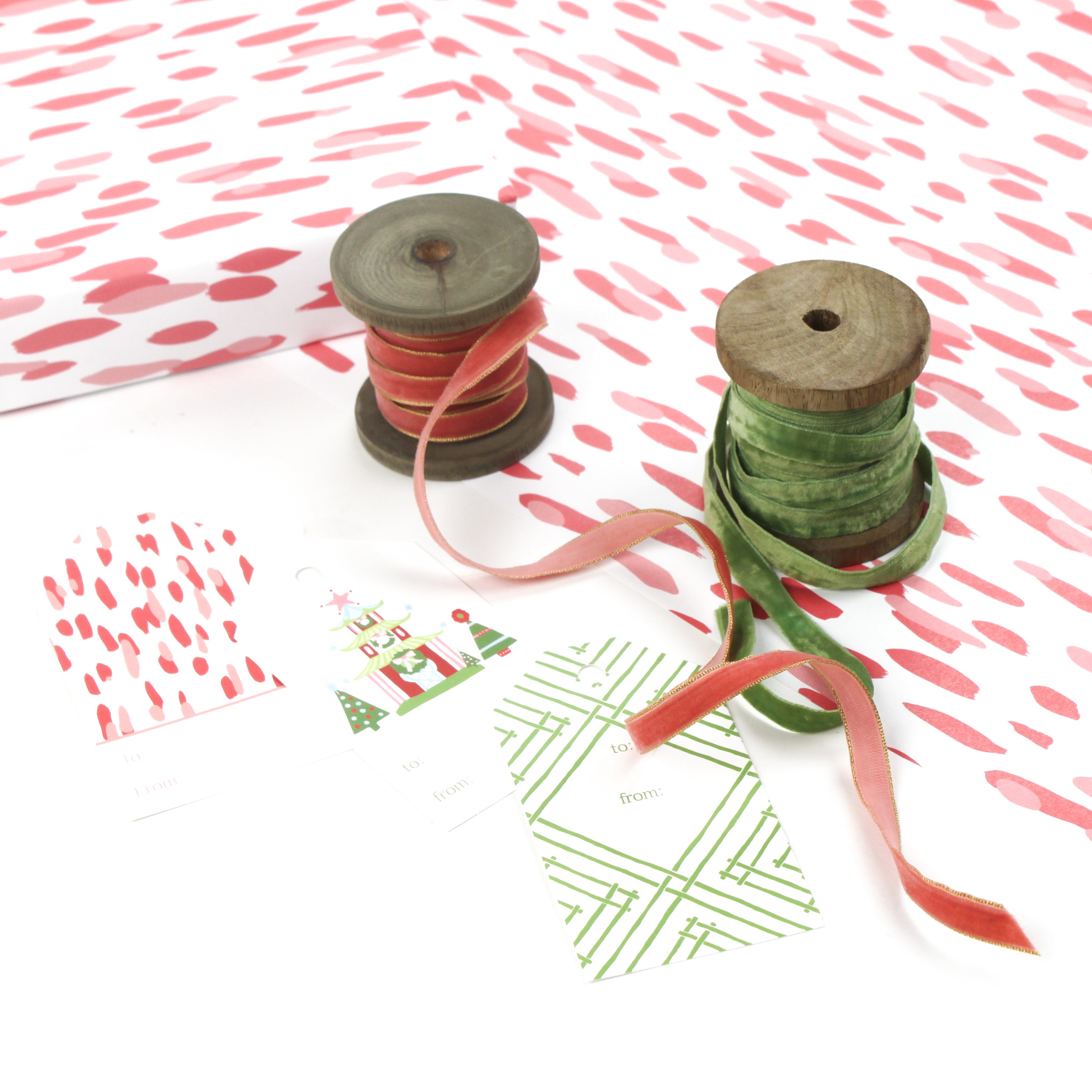 Styled display of pink brushstroke wrapping paper with ribbons and gift tags.