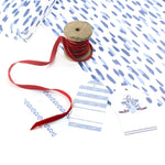 Styled display of blue brushstroke wrapping paper with red ribbon and gift tags.