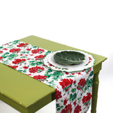 Red and green floral table runner styled on a green table with festive holiday plates.