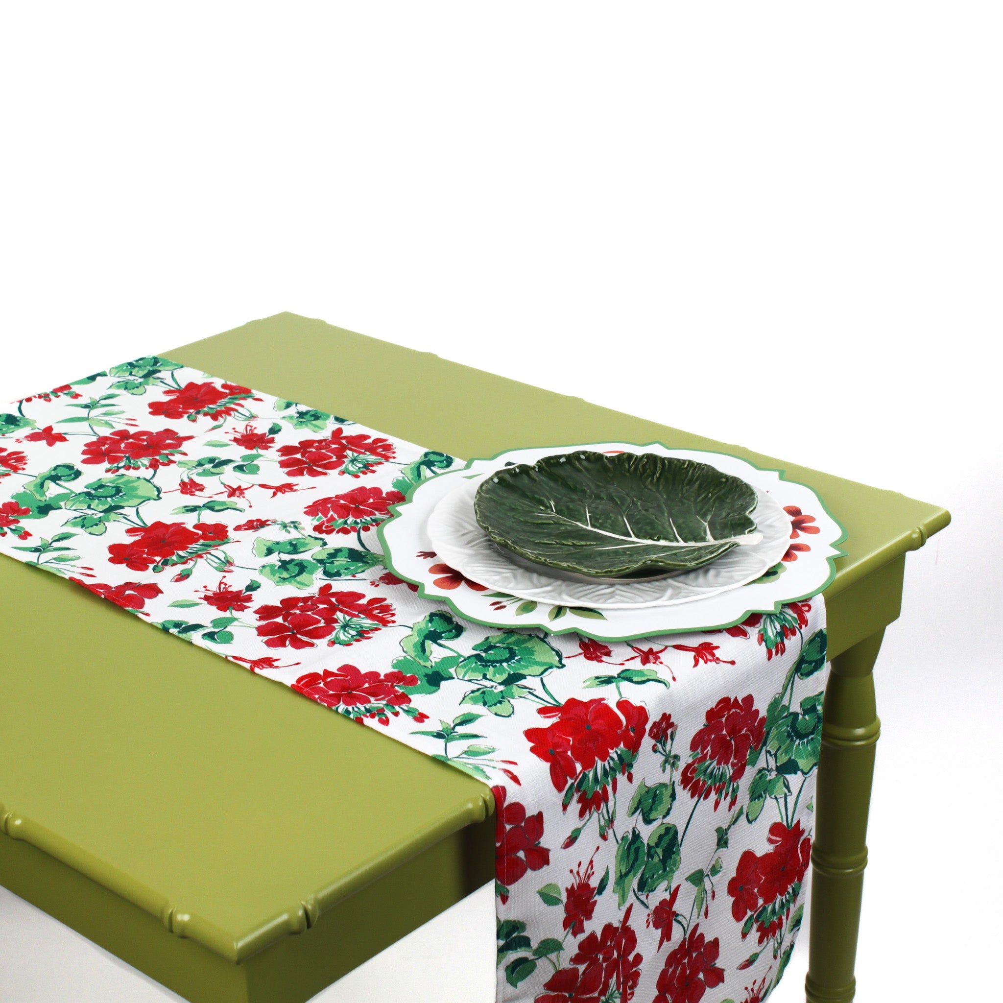 Red and green floral table runner styled on a green table with festive holiday plates.
