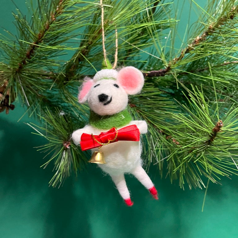 A felt mouse ornament wearing a green scarf and hat holds a red bow with a small gold bell hanging from it.