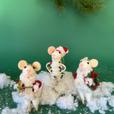 Three white felt mouse ornaments dressed in cozy winter outfits, one wrapped in colorful holiday lights, one holding a Christmas wreath, and one holding a festive ornament
