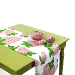 Styled strawberry table runner on a green table with pink ceramic bowls.