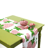Styled strawberry table runner on a green table with pink ceramic bowls.