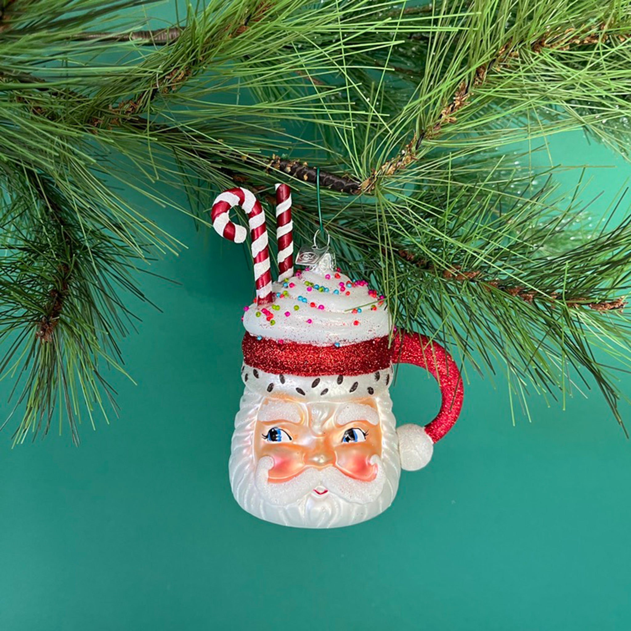 Glass Santa Mug with Glitter Candy Cane Christmas Ornament hanging in a branch