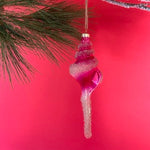 Decorative Christmas glass shell ornament hanging on a tree branch with a red background
