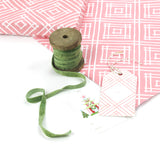 Gift box wrapped in red and white geometric patterned paper with green ribbon and a decorative gift tag.