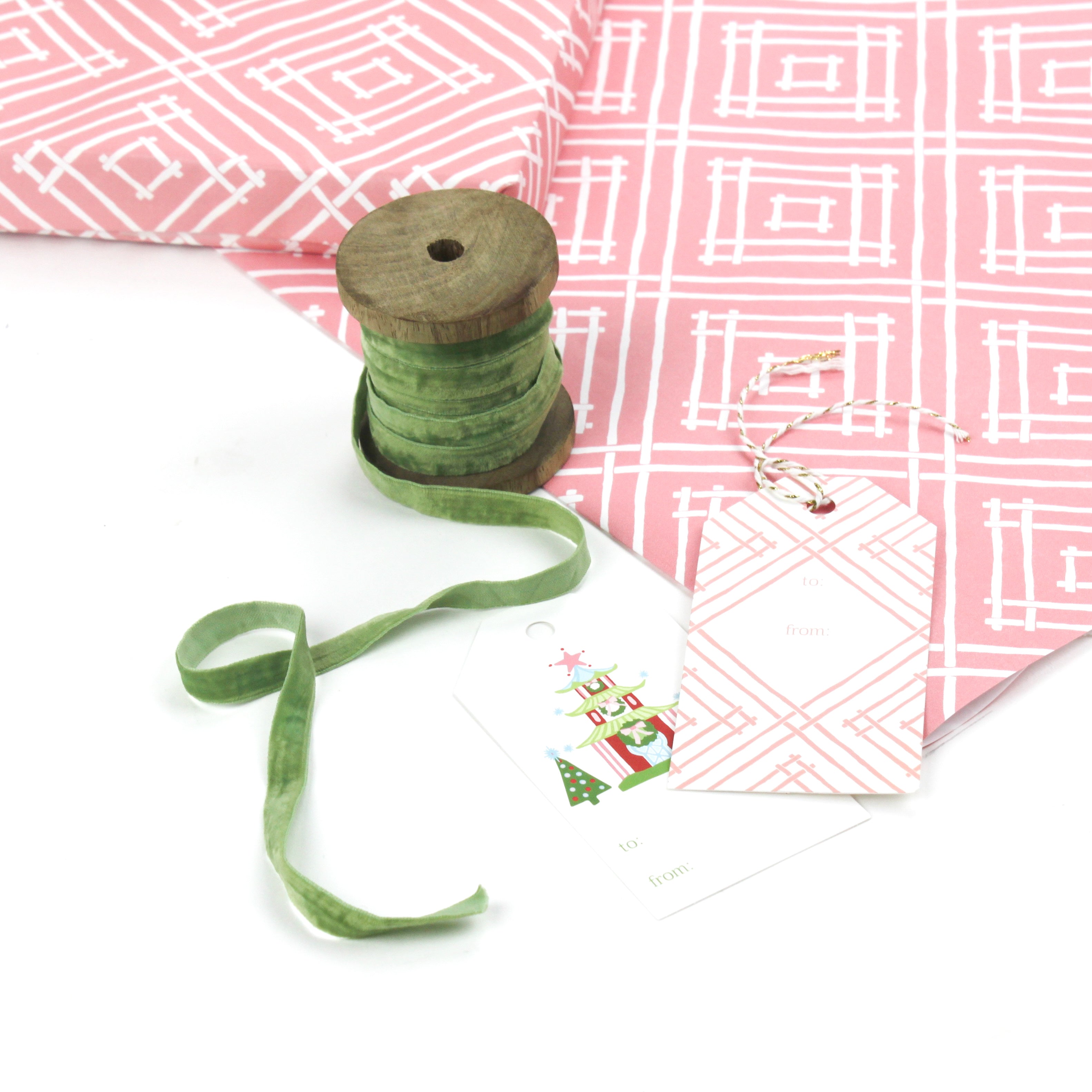 Gift box wrapped in red and white geometric patterned paper with green ribbon and a decorative gift tag.