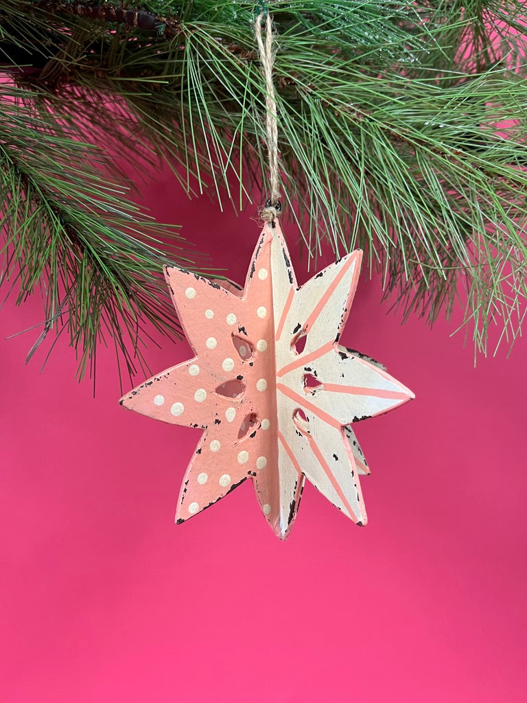 a large wooden star christmas ornaments painted in pink and white with distressed polka dot details