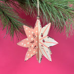 a large wooden star christmas ornaments painted in pink and white with distressed polka dot details