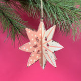 a large wooden star christmas ornaments painted in pink and white with distressed polka dot details