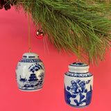 Two blue and white ginger jar ornaments hanging from a Christmas tree.