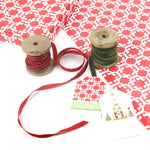 Monserrat red patterned wrapping paper styled with ribbons and gift tags.