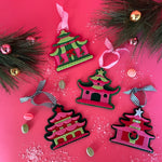 four pink felt chinoiserie christmas ornaments in the shape of pagodas against a white background 