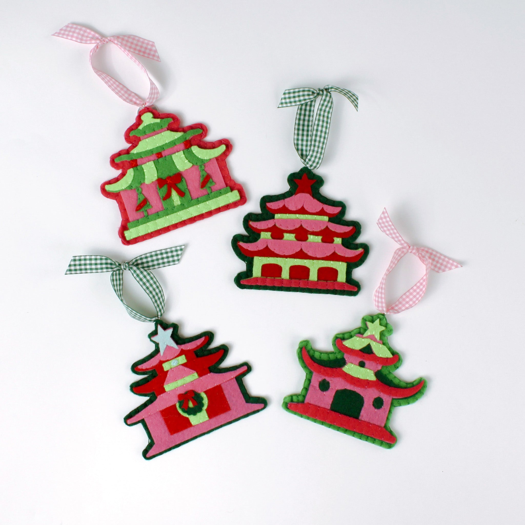 four pink felt chinoiserie christmas ornaments in the shape of pagodas against a white background 