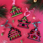 four pink felt chinoiserie christmas ornaments in the shape of pagodas against a white background 