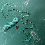 a recycled torn-silk ribbon in aqua laid in a green surface