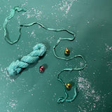 a recycled torn-silk ribbon in aqua laid in a green surface