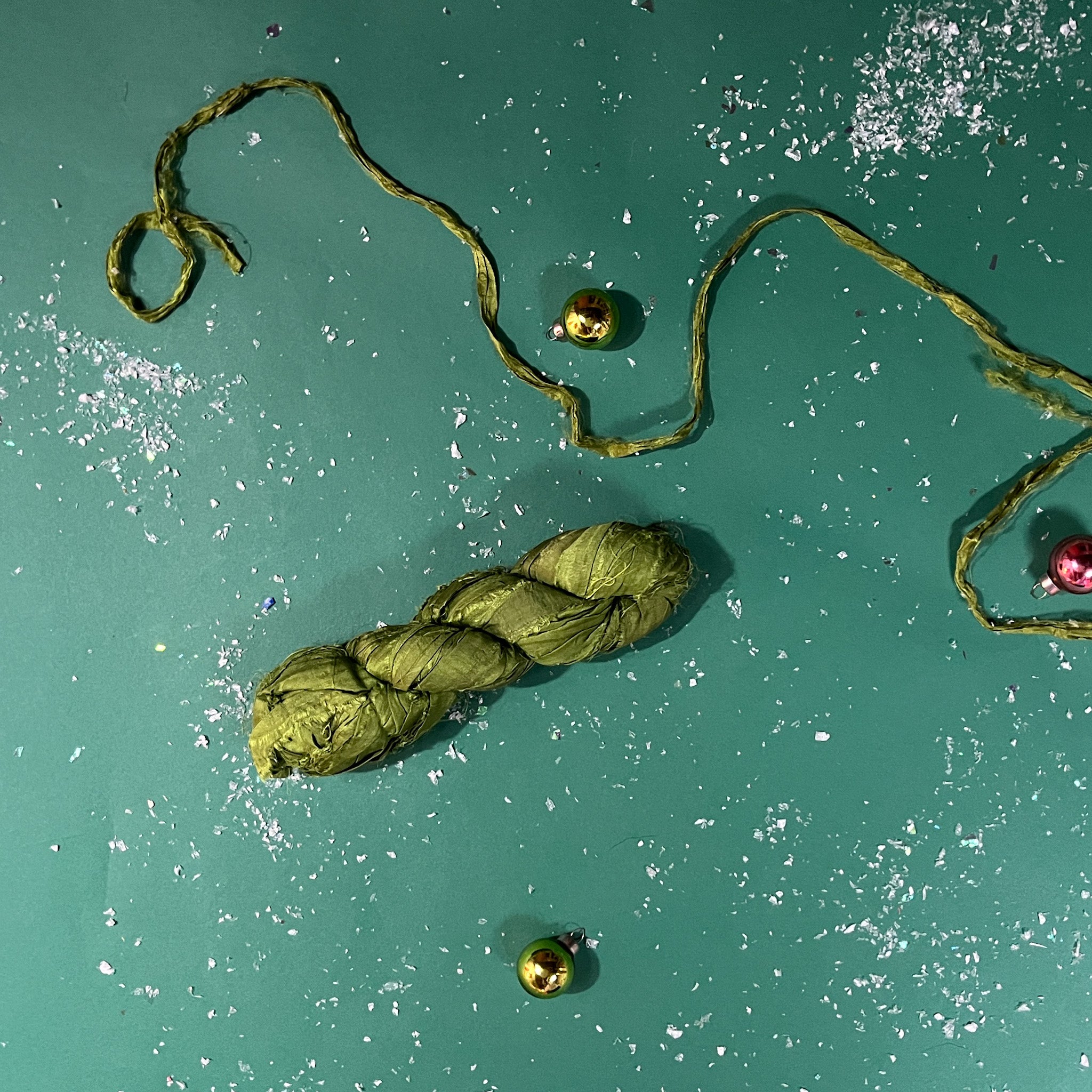a recycled torn-silk ribbon in green laid in a green surface