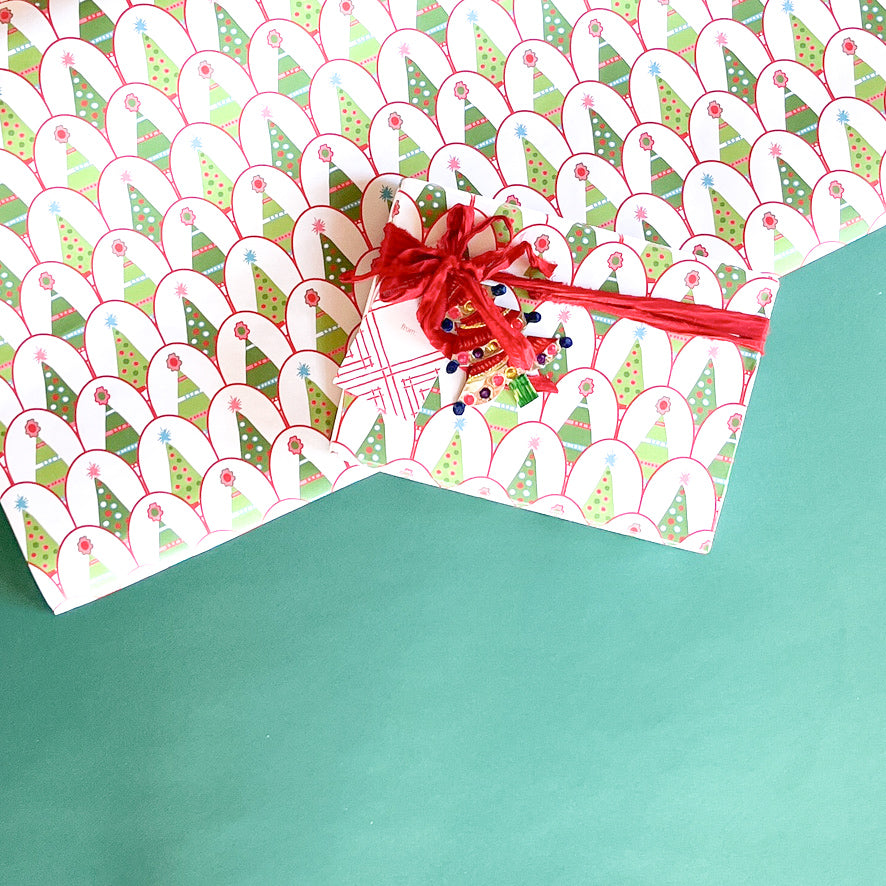 Twinkle Trees Christmas wrapping paper styled with wrapped gift, red ribbon, and matching patterned sheet.