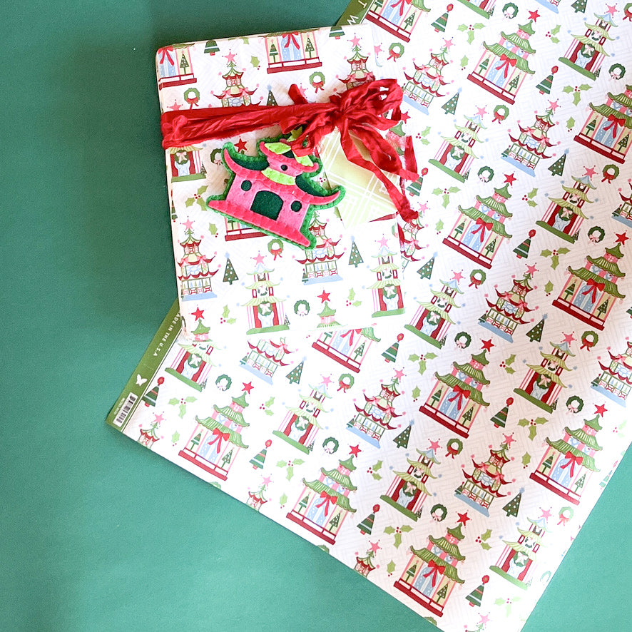Gift wrapped in pagoda Christmas print paper with red ribbon and matching holiday tag.