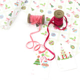 Holiday wrapping paper with Christmas ornament pattern displayed with ribbon spools and gift tags.