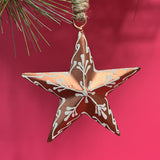 a copper star christmas ornament against a red background. 