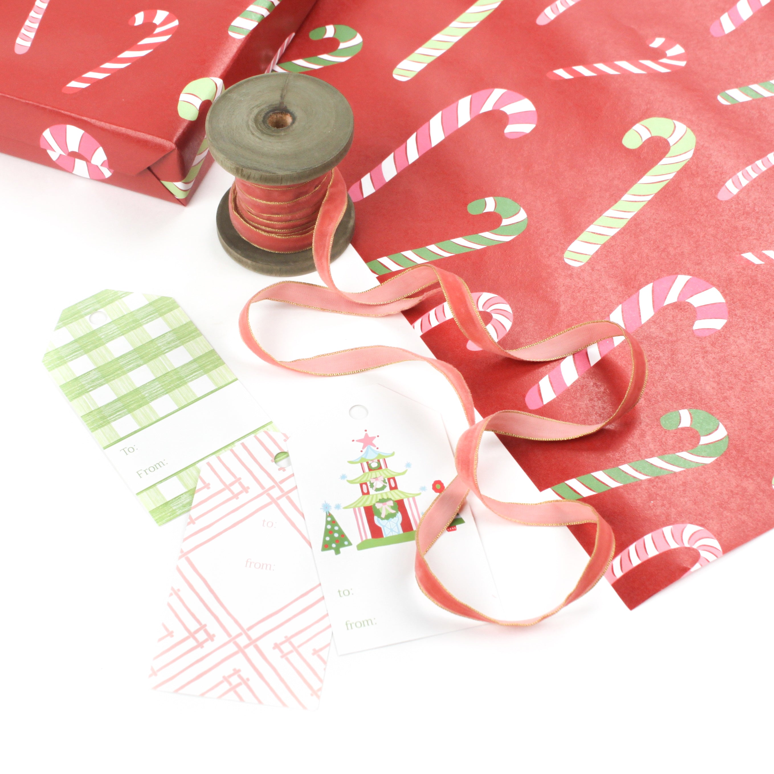 Styled display of red candy cane wrapping paper with ribbons and assorted gift tags.