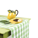 a green table covered by a Gin Lane Green Gingham Paper Table Runner on a white background