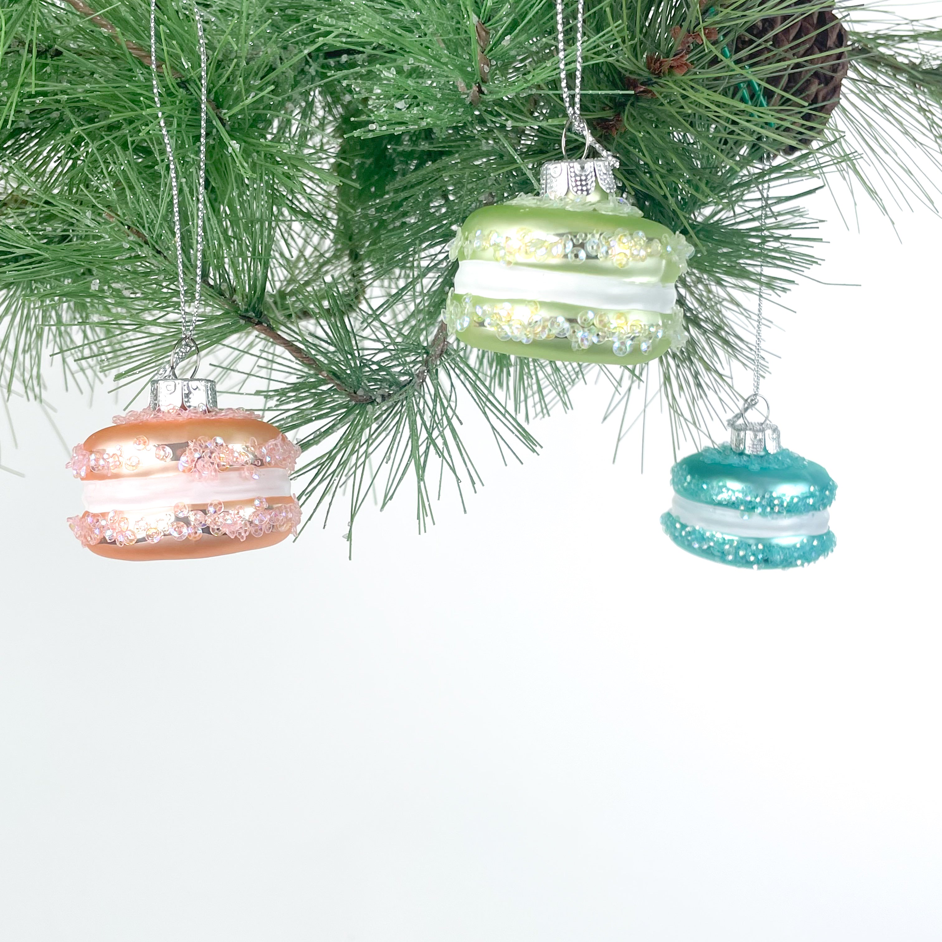 Decorative Christmas ornaments shaped like macarons hanging on a tree.