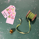 a light green Velvet Ribbon on Wood Spool in a green background with some gift tags on the side and gold ball ornaments