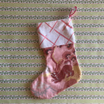 a pink christmas stocking with a pink and white lattice design cuff and a pink and yellow chinoiserie pattern stocking. 