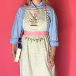 Person wearing Madcap cottage apron with pagoda design and pink straps on a red background