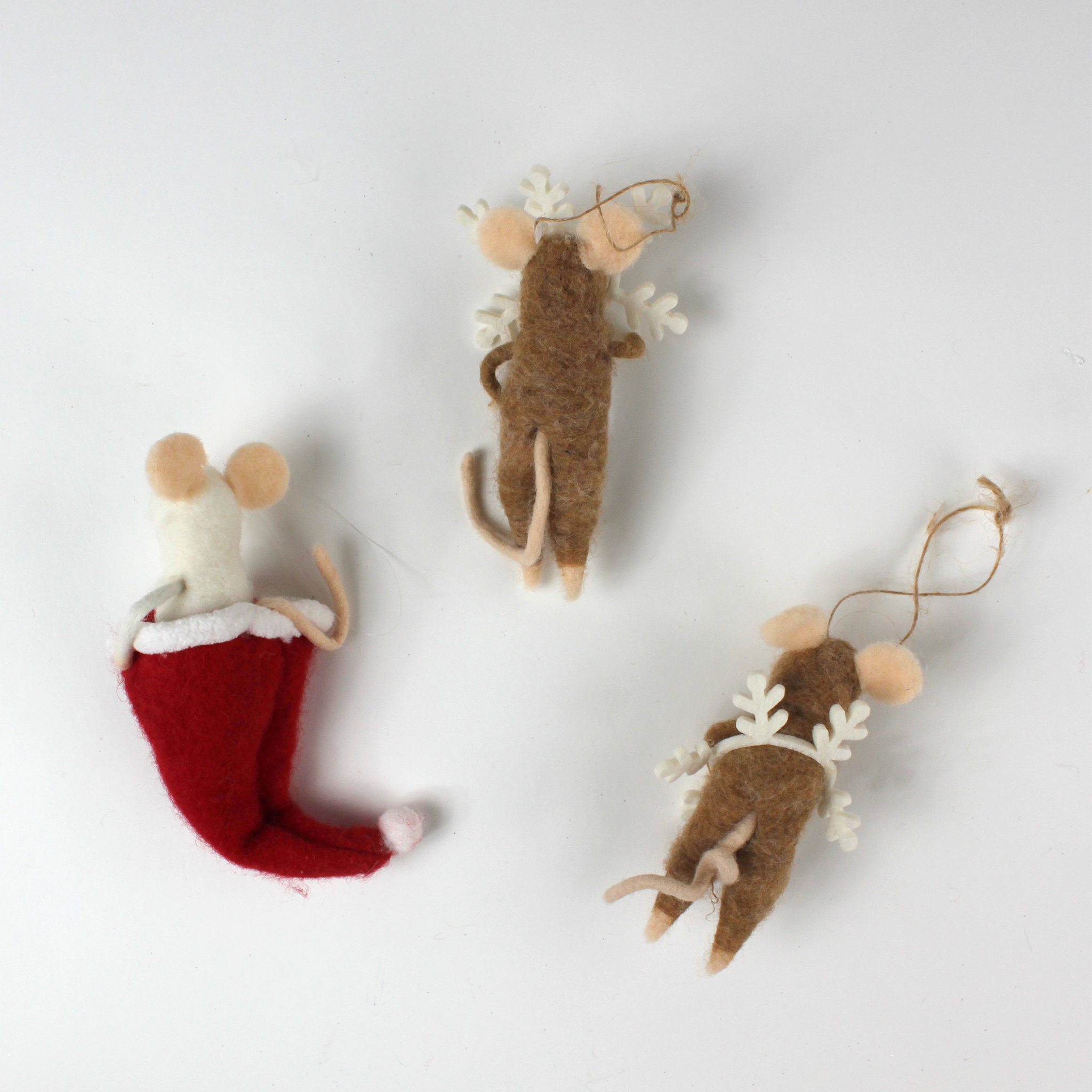 back of the Three felt mouse ornaments, one peeking out of a red Christmas stocking and two wearing white snowflake costume frames, shown lying flat