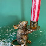 a gold red and white striped taper candle on a gold mice holder with a green background