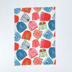 a madcap cottage christmas tea towel with colorful holiday sweater pattern in red, green and blue on a white background