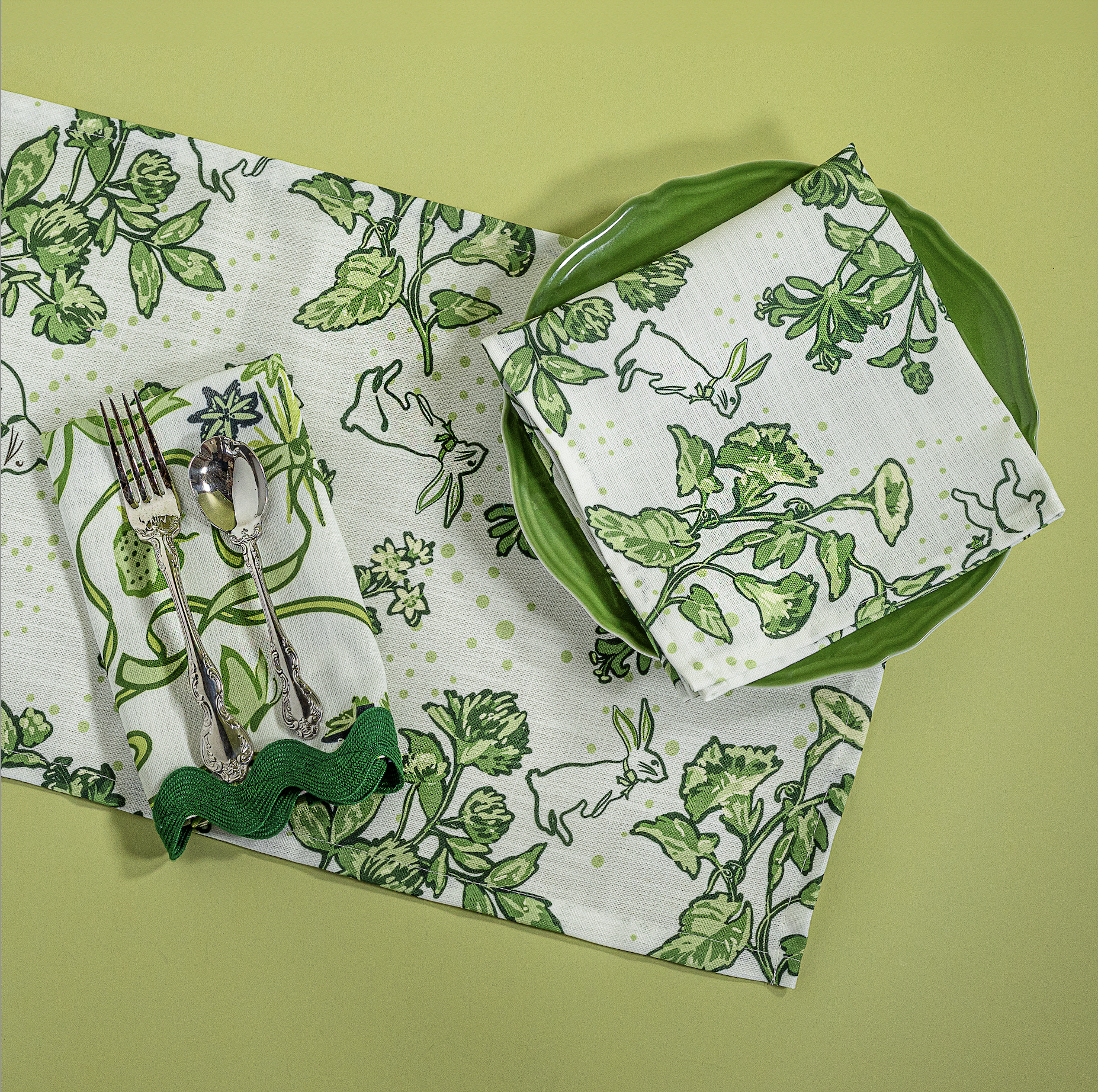 a springtime strawberry print fabric easter table runners in green with a plate, napkin and cutlery
