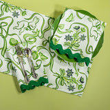 Bunnies and bow print fabric easter napkins in green with cutlery and plate against a green background. 