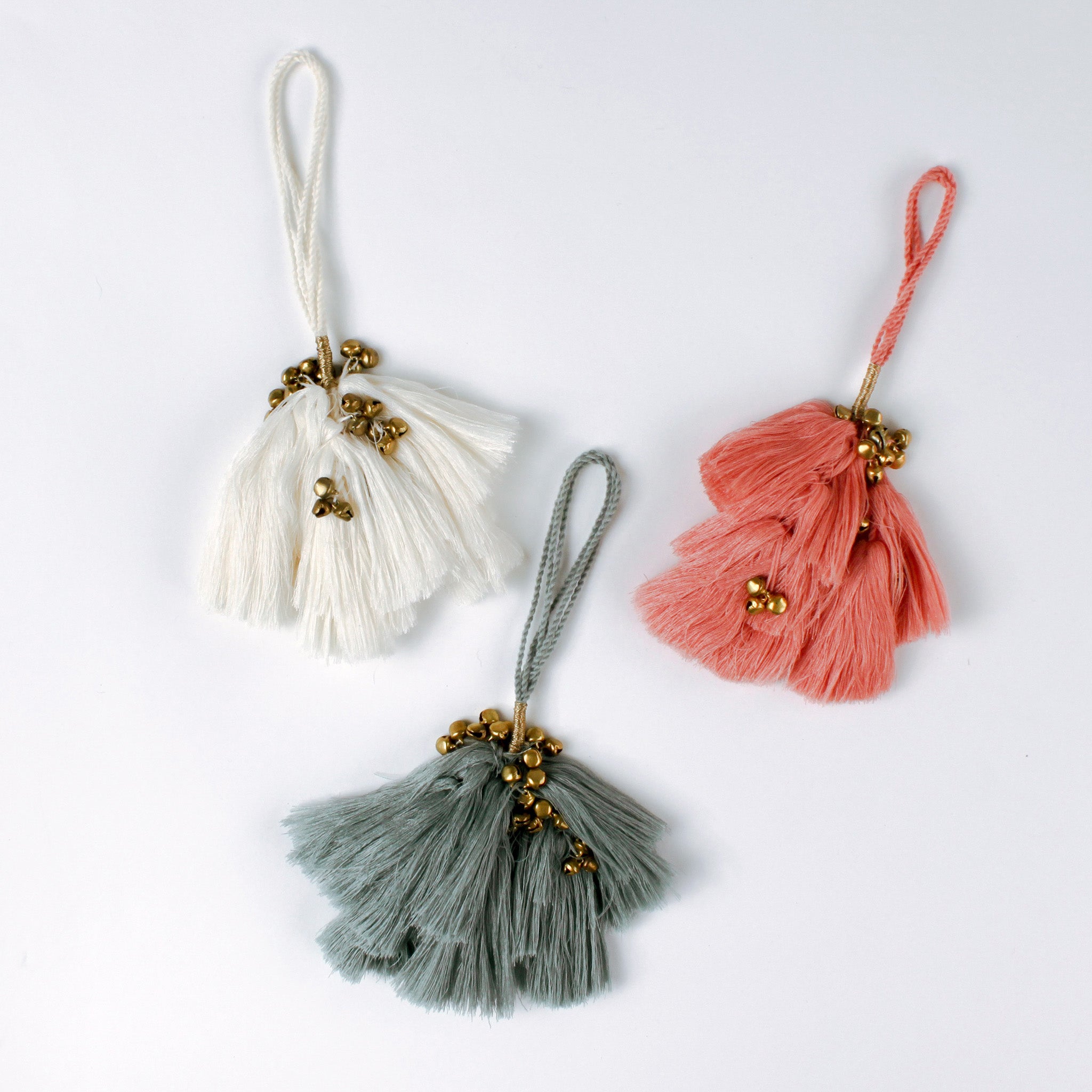 Set of three elegant tassel Christmas ornaments in white, coral and blue with small gold bells