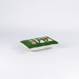 Rectangular green decorative pillow with a hooked texture, featuring a colorful pattern of golf tees in white, red, blue, yellow, and peach tones lying in a white surface